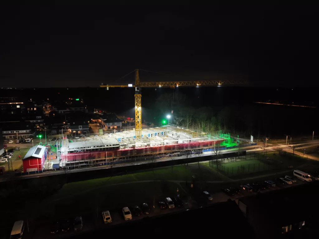 Obra de HSB en Hilversum por la noche, iluminada desde la grúa torre, vista desde la calle